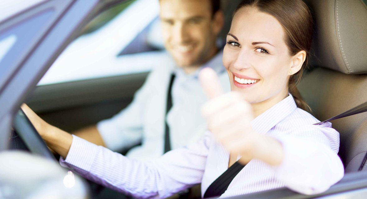 Zwei fröhliche Personen in Fahrzeug sitzend mit Daumen hoch Geste bei geöffnetem Fenster
