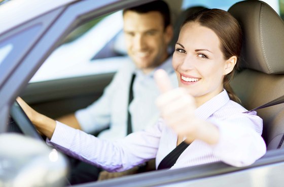 Zwei fröhliche Personen in Fahrzeug sitzend mit Daumen hoch Geste bei geöffnetem Fenster